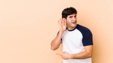 Bej arka planda izole edilmiş genç bir adam bir dedikoduyu dinlemeye çalışıyor..