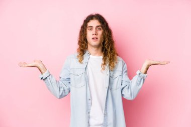 Yalnız poz veren uzun saçlı adam kollarıyla ölçek yapar, mutlu ve kendinden emin hisseder..