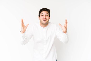 Beyaz arka planda izole genç bir adam hoş bir sürprizle karşılaşıyor, heyecanlı ve el kaldırıyor..