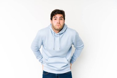 Beyaz arka planda izole edilmiş genç adam omuz silkiyor ve gözleri açık..