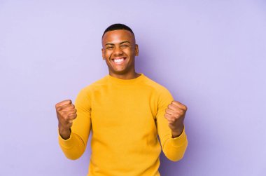 Mor arka planda yalnız kalmış genç latin adam kaygısız ve heyecanlı tezahüratlar yapıyor. Zafer konsepti.