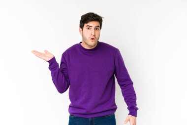 Beyaz arka planda izole edilmiş genç adam, avuç içinde kopya alanı tutmaktan etkilenmiş..