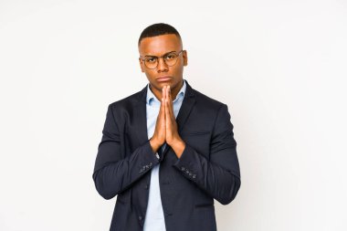 Genç iş adamı beyaz arka planda izole edilmiş, el ele tutuşmuş, ağzı yakınında dua eden, kendinden emin..