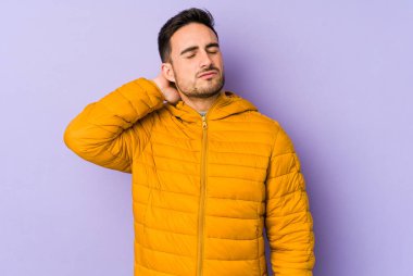 Mor arka planda izole olmuş genç beyaz bir adam stresten dolayı boynu ağrıyor, masaj yapıyor ve elle dokunuyor..