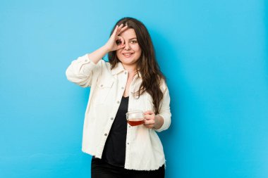 Genç, kıvrımlı bir kadın elinde çay fincanı tutarken heyecanlanıyor..