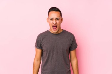 Pembe arka planda poz veren yog latin adam çok sinirli ve agresif bağırıyor..