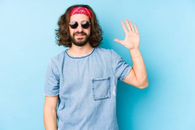 Genç, uzun saçlı, festival elbisesi giyen hippi görünüşlü beş numarayı parmaklarıyla gülümseyen biri..