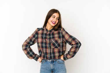 Beyaz arka planda izole edilmiş beyaz tenli genç bir kadın ellerini kalçasından ayırmıyor..