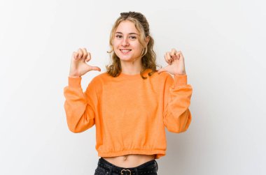 Beyaz arka plandaki genç beyaz kadın kendini gururlu ve kendinden emin hissediyor..