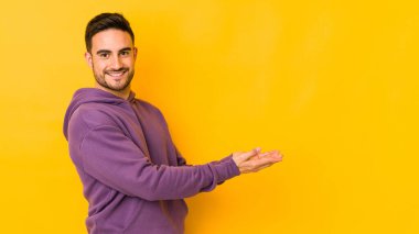 Kafkasyalı genç adam sarı fırında izole edilmiş. Elinde palmiye ağacının üzerinde bir kopyası var..