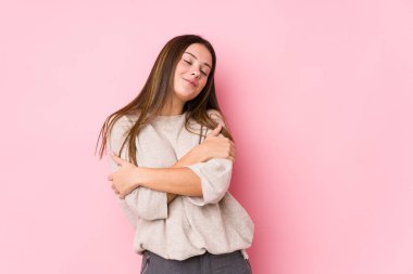 Kafkasyalı genç bir kadın, yalıtılmış sarılmalar sergiliyor, kaygısız ve mutlu bir şekilde gülümsüyor..