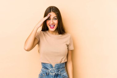 Beyaz tenli genç kadın bej arka planda izole edilmiş yüksek sesle bağırıyor, gözleri açık ve elleri gergin tutuyor..