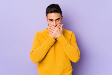 Mor arka planda izole edilmiş genç beyaz adam elleri ve ağzı endişeli görünüyor..