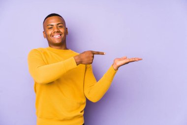 Mor arka planda izole edilmiş genç latin adam, elinde bir fotokopi alanı tutarken heyecanlı..