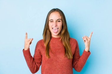 Genç beyaz kadın izole edilmiş poz veriyor. Parmaklarıyla kaya hareketi yapıyor.