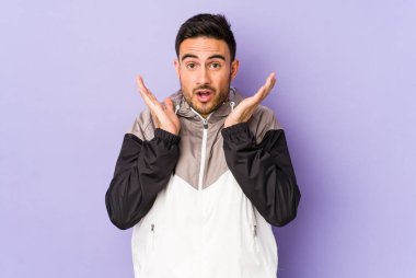 Mor arka planda izole genç beyaz adam şaşırdı ve şok oldu..