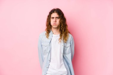 Uzun saçlı adam yalnız poz veriyor, yanakları patlatıyor, yorgun bir ifadesi var. Yüz ifadesi kavramı.