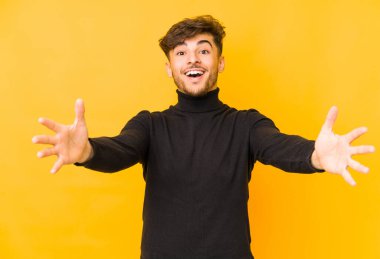 Sarı arka planda izole edilmiş genç bir Arap adam kameraya sarıldığı için kendinden emin hissediyor..