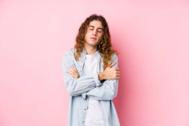 Uzun saçlı adam yalıtılmış sarılmalar sergiliyor, kaygısız ve mutlu gülümsüyor..