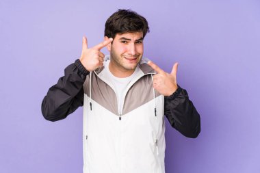 Mor arka planda izole genç adam işaret parmağıyla bir hayal kırıklığı jesti gösteriyor..