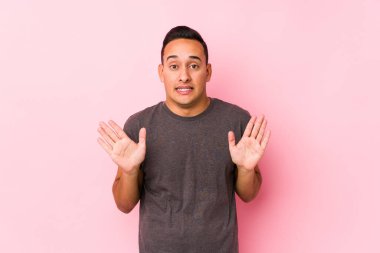 Pembe arka planda poz veren yog latin adam tiksinti belirtisi gösteren birini gösteriyor..