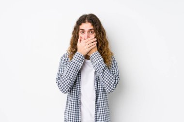 Genç, uzun saçlı, yalnız poz veren, ağzı elleriyle örten, şok olmuş bir adam..