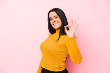 Genç, beyaz bir kadın pembe arka planda izole edilmiş neşeli ve kendinden emin, iyi bir jest yapıyor..