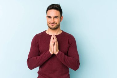 Kafkasyalı genç bir adam mavi arka planda izole edildi. Aklında bir plan kuruyor, bir fikir kuruyor..