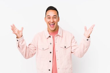 Yalnız poz veren genç Latin bir adam hoş bir sürpriz alıyor, heyecanlı ve el kaldırıyor..