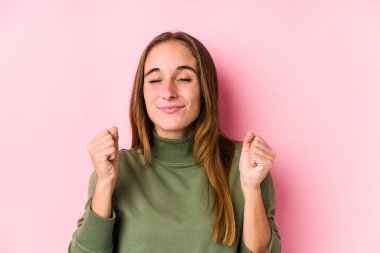 Kafkasyalı genç bir kadın münzevi poz veriyor yumruğunu kaldırıyor, mutlu ve başarılı hissediyor. Zafer konsepti.