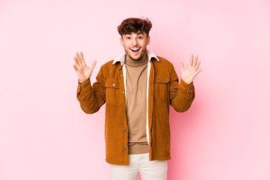 Pembe arka planda yalnız poz veren genç bir Arap.