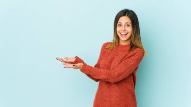 Mavi arka planda izole edilmiş genç bir kadın avucunun içinde bir kopya alanı tutuyor..