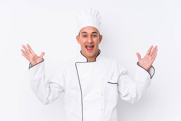 Young latin chef man isolated receiving a pleasant surprise, excited and raising hands.