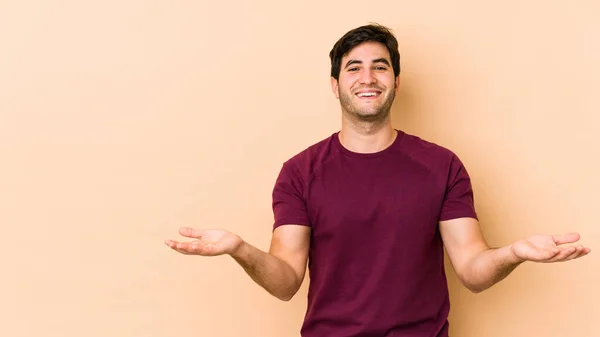 Jovem Isolado Fundo Bege Faz Escala Com Braços Sente Feliz — Fotografia de Stock