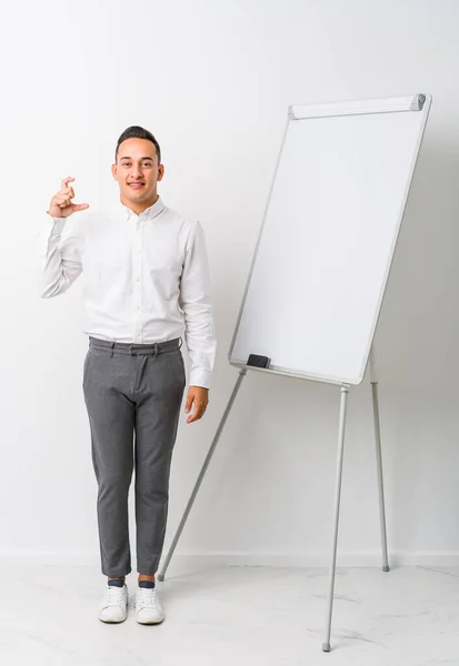 Young Latin Coaching Man Whiteboard Isolated Holding Something Little Forefingers — Stock Photo, Image