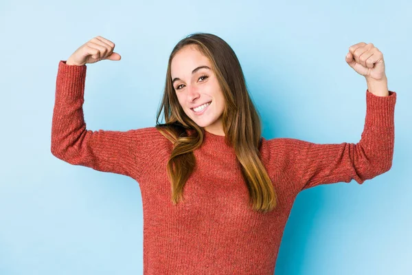 Young caucasian woman posing isolated  showing strength gesture with arms, symbol of feminine power