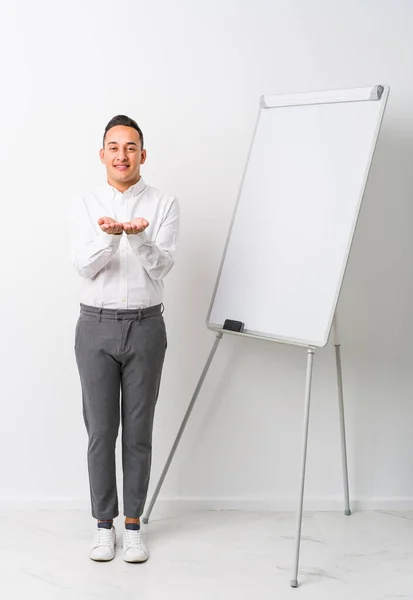 Young Latin Coaching Man Whiteboard Isolated Holding Something Palms Offering — Stock Photo, Image