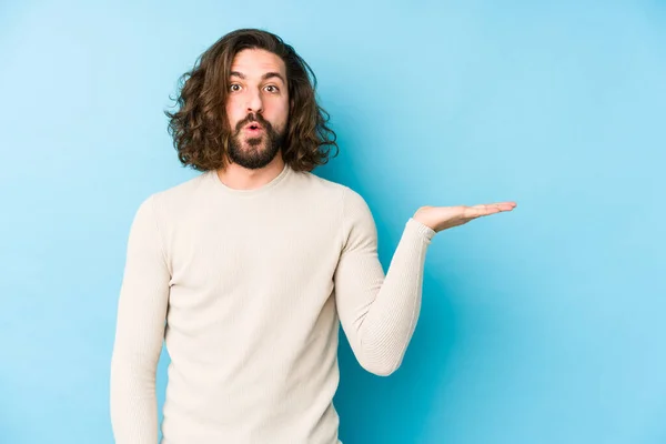 Young Long Hair Man Isolated Blue Background Impressed Holding Copy — Stock Photo, Image