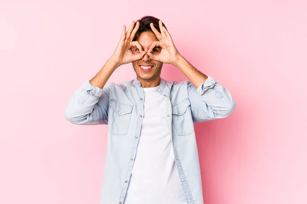 年轻的高加索男子 身披粉红的背景 与外界隔离 在眼睛上显示出良好的迹象 — 图库照片