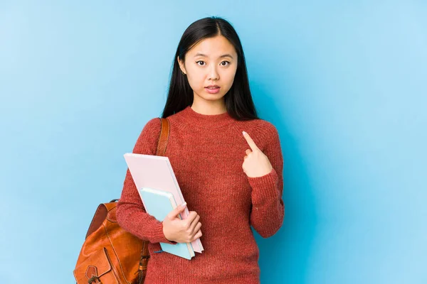 Young chinese student woman isolated pointing with finger at you as if inviting come closer.