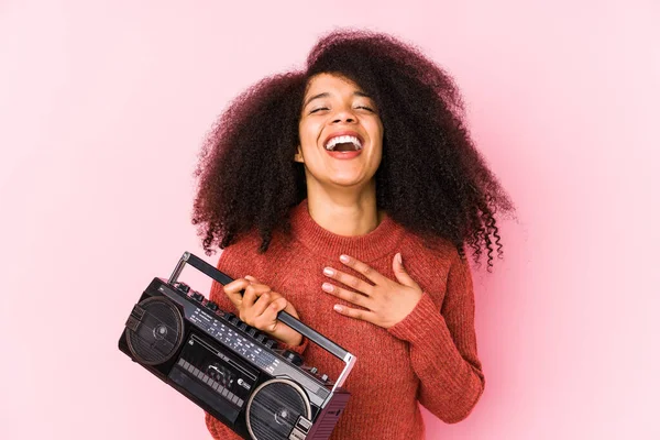 Elinde kaset tutan genç bir afro kadın kahkahalar atıyor ve elini göğsüne koyuyor..