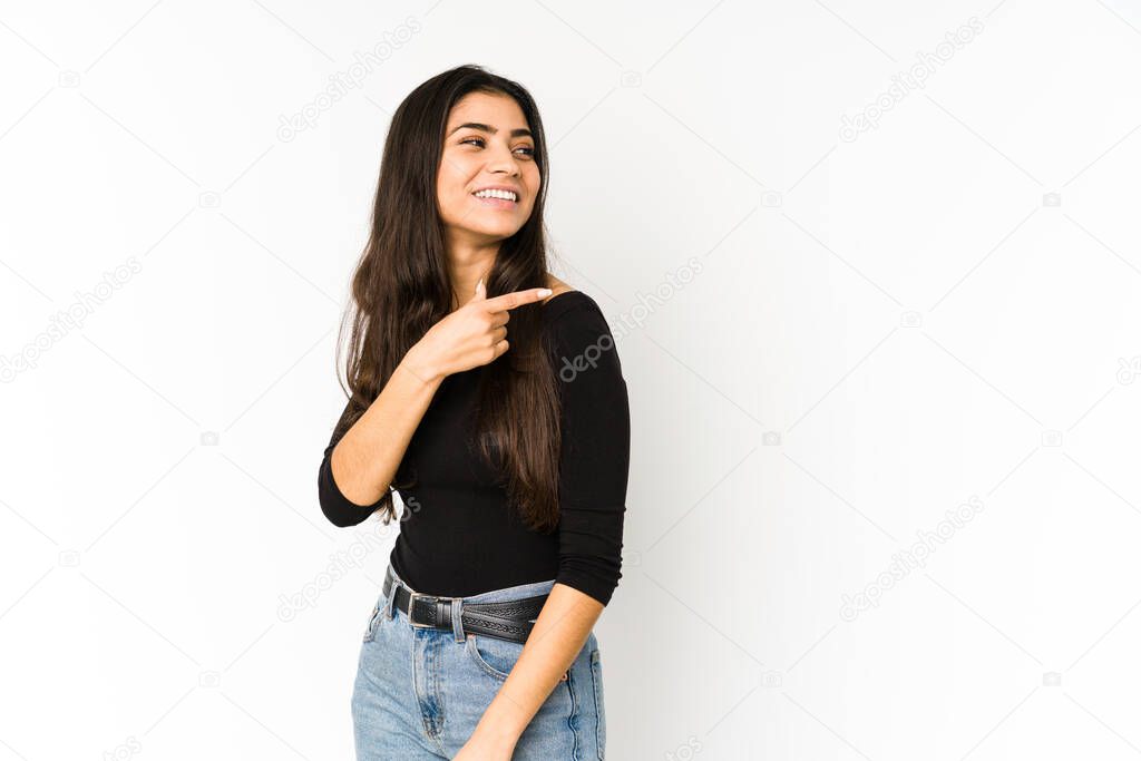 Young indian woman isolated on purple background looks aside smiling, cheerful and pleasant.