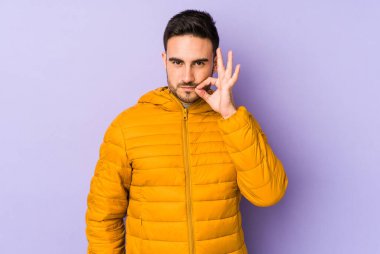 Mor arka planda izole edilmiş genç, beyaz bir adam dudaklarında parmaklarıyla bir sır saklıyor..