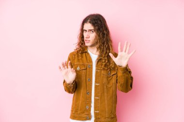 Genç, uzun saçlı bir adam dışlanmış poz veriyor. İğrenme belirtisi gösteren birini reddediyor..