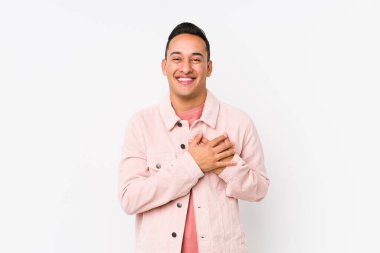 Genç Latin adam yalnızmış gibi gülüyor, ellerini kalbe koyuyor, mutluluk kavramını koruyor..