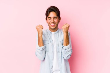 Pembe arka planda poz veren beyaz bir genç kendini mutlu ve başarılı hissediyordu. Zafer konsepti.