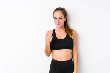 Beyaz arka planda poz veren beyaz tenli genç kadın sanki seni davet ediyormuş gibi seni işaret ediyor..