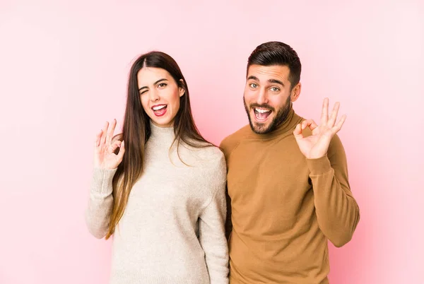 Giovane Coppia Caucasica Isolato Strizza Occhio Tiene Gesto Con Mano — Foto Stock