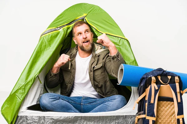 Beyaz arka planda izole edilmiş bir çadırın içinde zafer kazandıktan sonra yumruğunu kaldır, kazanan konsept..