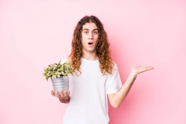 Lang Haar Kaukasische Man Met Een Plant Onder Indruk Houden — Stockfoto